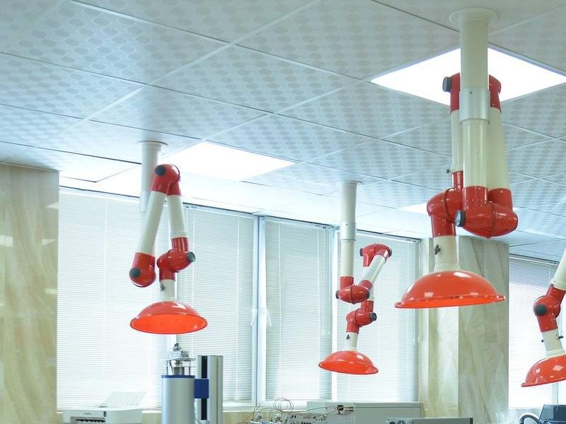 Ceiling-mounted articulated extraction arms over a laboratory bench